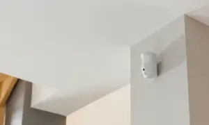Détecteur de mouvement blanc fixé dans un coin, prêt à fabriquer une alarme.