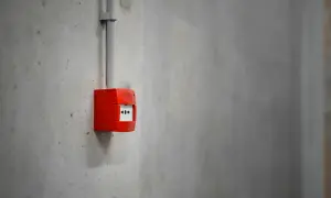 Découvrez comment fonctionne une alarme incendie : un boîtier rouge sur un mur en béton, prêt à alerter en cas de danger.