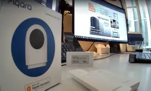 Boîte de l'aqara g2h pro, un hub caméra HomeKit, posée sur un bureau avec un écran d'ordinateur affichant des produits domotiques.