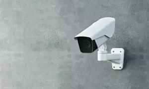 Une caméra de surveillance blanche est fixée sur un mur de béton. Cette caméra sans internet assure une sécurité discrète.