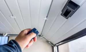 Main tenant utilise une télécommande pour motoriser une porte de garage.