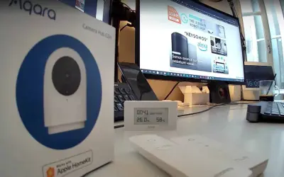 Boîte de l'aqara g2h pro, un hub caméra HomeKit, posée sur un bureau avec un écran d'ordinateur affichant des produits domotiques.