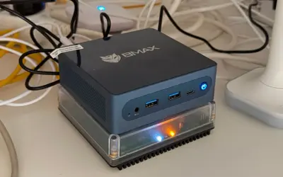 Un mini-PC BMAX, prêt à assister Gladys, est allumé sur un socle transparent.