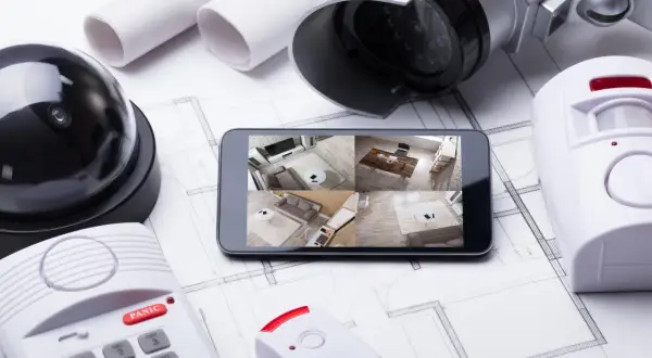 Kit d'alarme à installer soi même : caméra, détecteur de mouvement, centrale et smartphone affichant les flux vidéo.