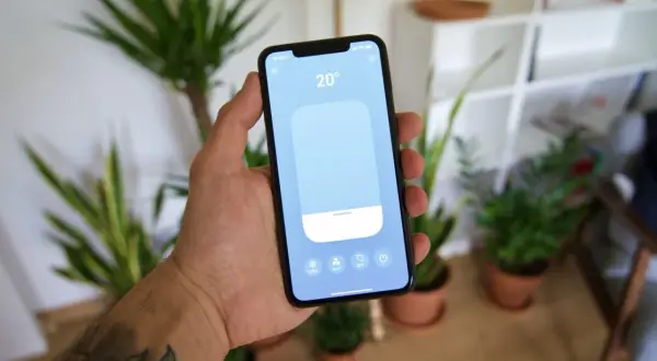 Main tenant contrôle la température de sa maison avec une application tado homekit sur son smartphone.