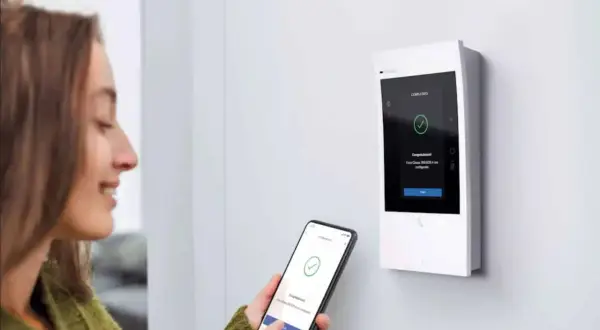 Une femme utilise son smartphone pour configurer un interphone Bticino Classe 300. L'écran affiche "Completato".
