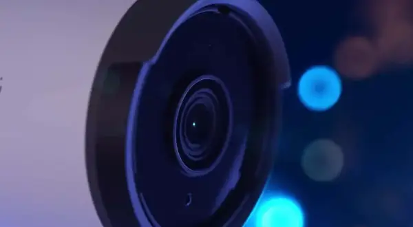 Gros plan sur l'objectif d'une caméra de surveillance, avec des lumières bleues floues en arrière-plan, évoquant le stockage vidéo surveillance.