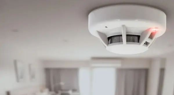 Détecteur de fumée blanc au plafond, voyant rouge allumé. Il est temps de changer la pile de ce détecteur de fumée insafe.