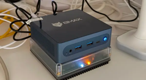 Un mini-PC BMAX, prêt à assister Gladys, est allumé sur un socle transparent.
