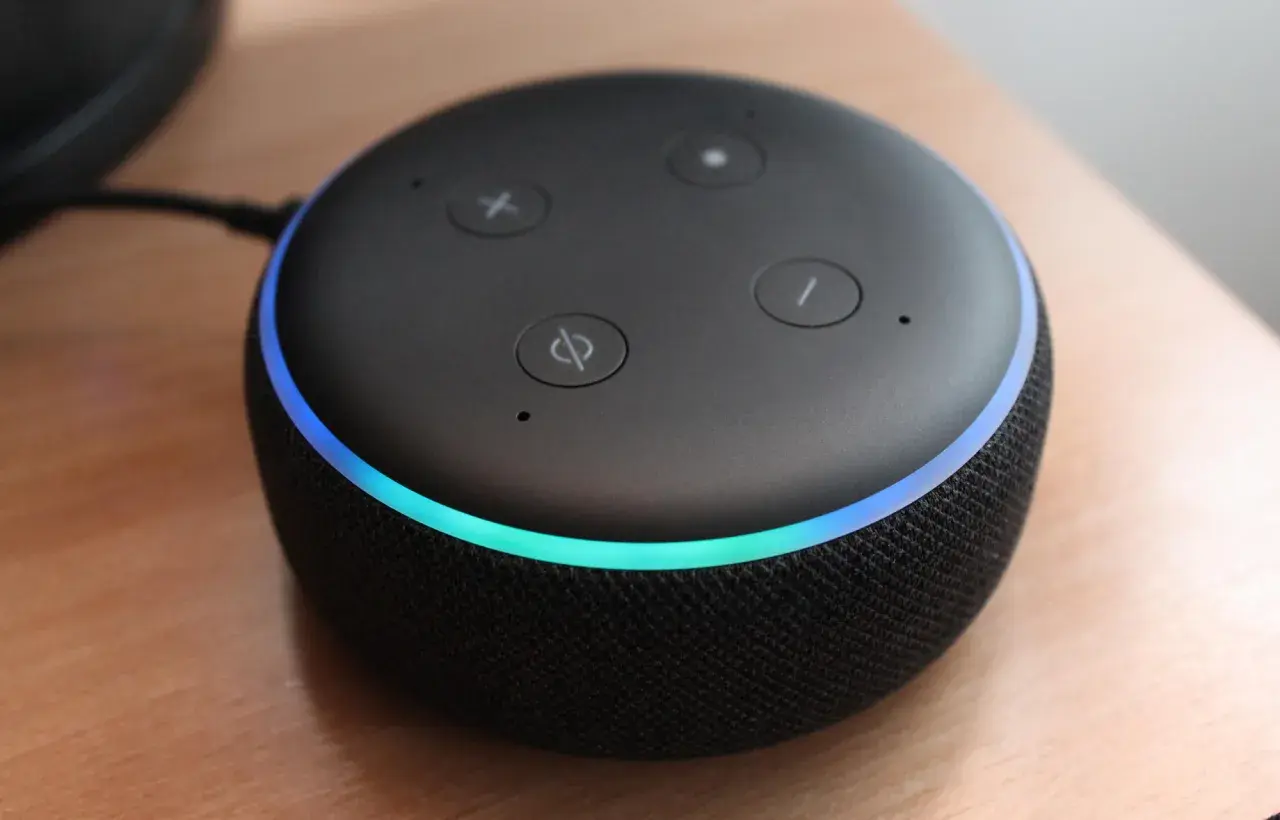 Une enceinte connectée Alexa avec un anneau lumineux bleu et vert, prête à connecter au wifi.