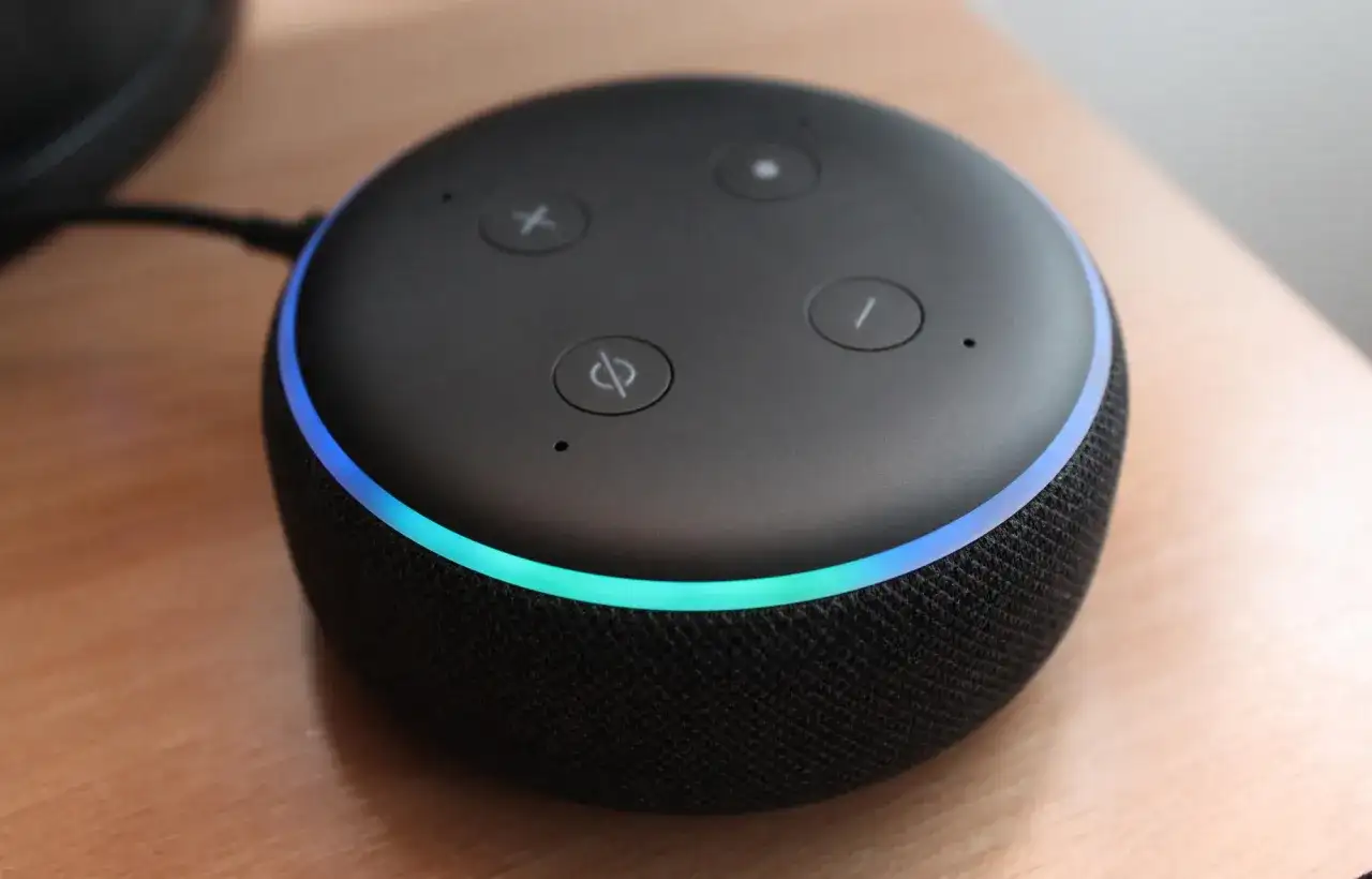 Une enceinte connectée Alexa avec un anneau lumineux bleu et vert, prête à connecter au wifi.