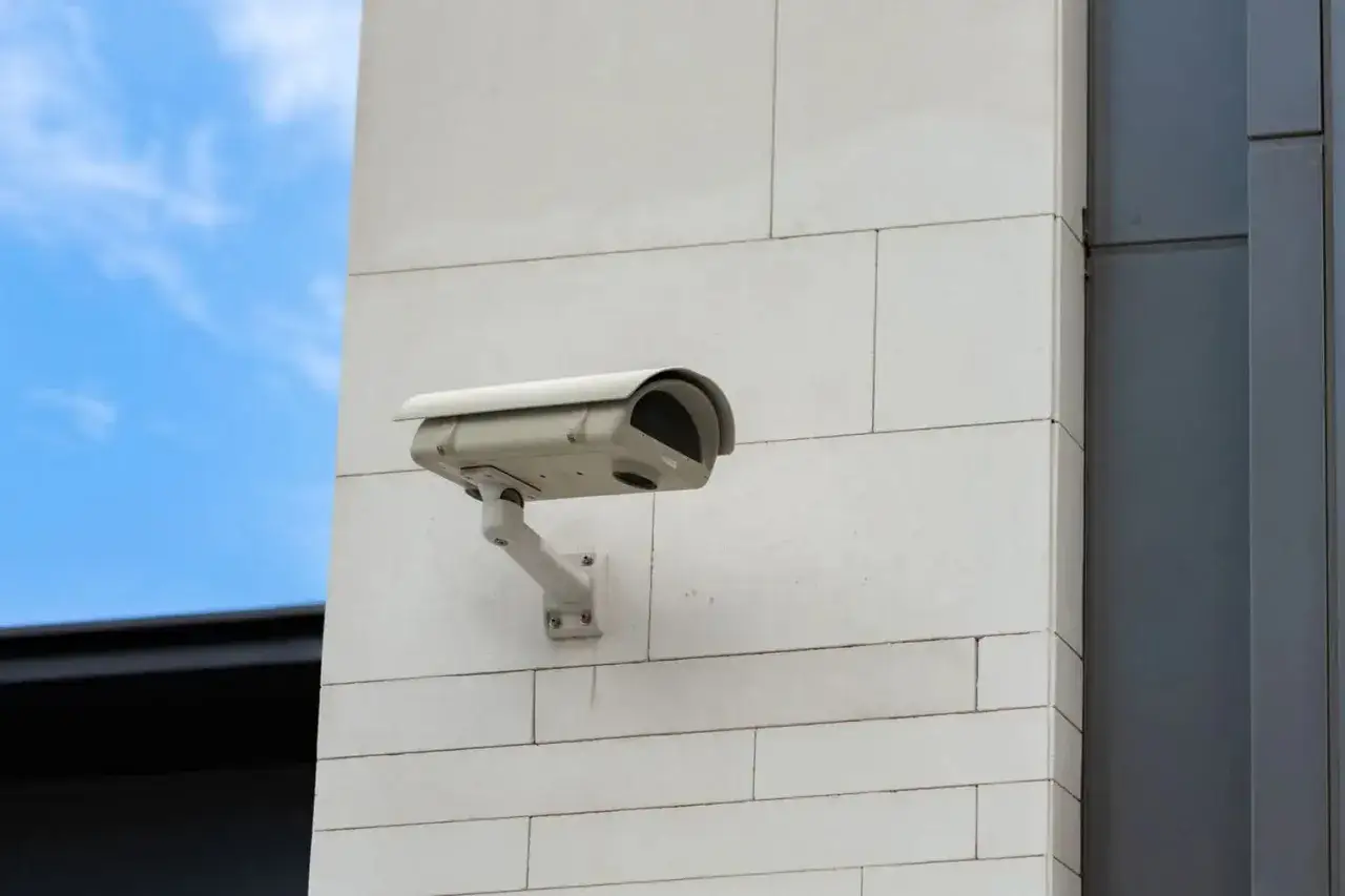 Cam&eacute;ra de surveillance fix&eacute;e sur un mur blanc, pr&ecirc;te &agrave; filmer. On peut imaginer quelqu'un cherchant &agrave; emp&ecirc;cher une cam&eacute;ra de filmer.