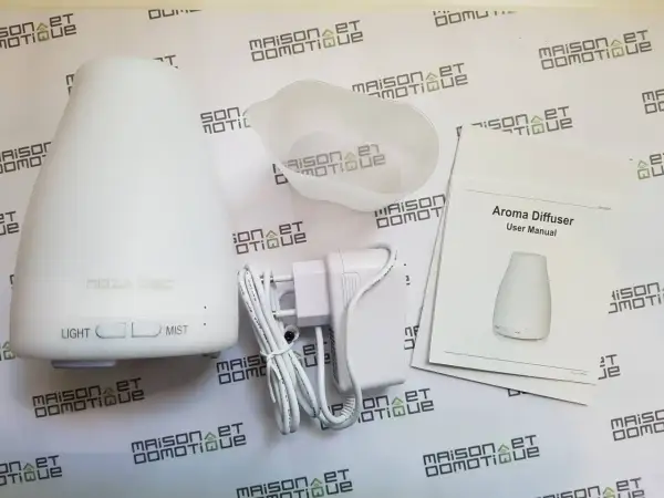Un diffuseur d'arômes blanc, son adaptateur et son manuel. Un objet connecté pour une ambiance olfactive personnalisée.
